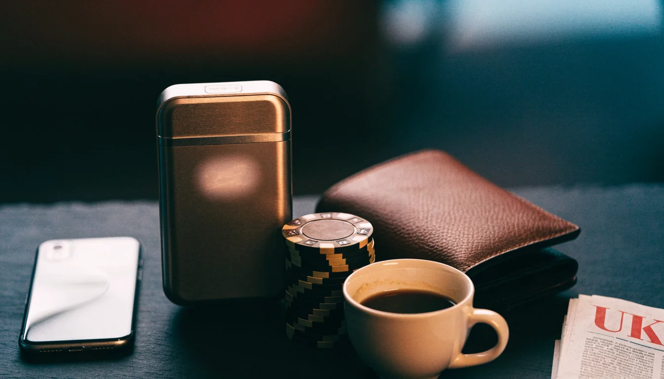 Smartphone, contactless card reader, and casino chips on a dark table suggesting online payment.